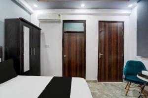 a bedroom with a bed and a door and a chair at Hotel O The smart haven in Ghaziabad