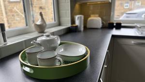 a tray filled with cups and teapots on a kitchen counter at Wisteria Cottage in Eyam