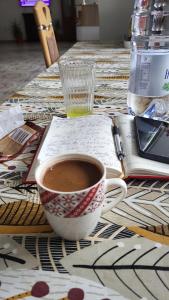 a cup of coffee and a book on a table at Pensiunea DEDU in Buşteni
