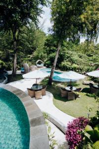 a swimming pool with chairs and umbrellas in a yard at Deep Roots Dive & Yoga Resort in Nusa Penida +61 photos