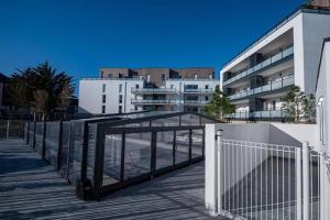a fence on a boardwalk in front of a building at Appartement port du Crouesty avec terrasse et piscine in Arzon