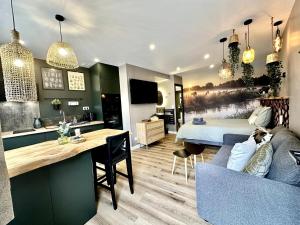 a room with a couch and a bed and a kitchen at l'Aure in Isigny-sur-Mer