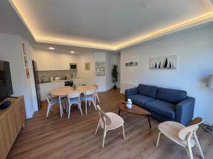 a living room with a blue couch and a table and chairs at Piso de lujo con gran terraza in Sanxenxo