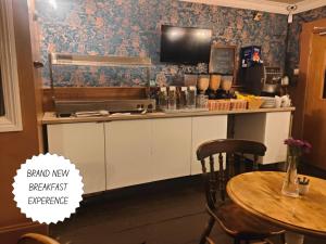 a kitchen with a table and a tv on the wall at The Royal Oak in Bere Regis