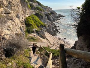 a person walking down a path near the ocean at Calamari Self Catering in De Kelders