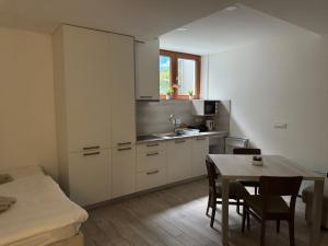 a kitchen with white cabinets and a table with chairs at U Izi 2 in Kranjska Gora