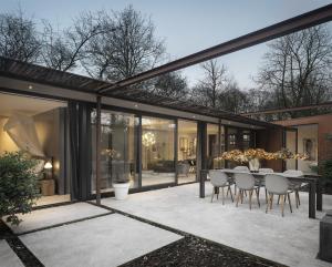 an extension of a house with a dining table and chairs at Stalen Boshuis by Droomvilla in Oosterhout