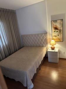 una camera da letto con un letto e una lampada sul comodino di Piscina,sauna ,ar condicionado a 30passos da Bacutia a Guarapari Altre 43 foto