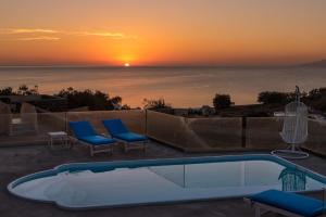 a pool with a view of the ocean at sunset at Queen of Santorini in Karterados