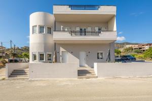 een wit gebouw met een balkon aan de zijkant bij Lume, Stylish New Apartment Near the Beach in Agia Pelagia