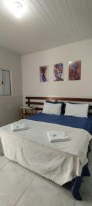 a bedroom with a large bed with two towels on it at Pousada Jamaica in Igarassú