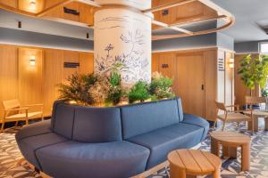 Un sofá azul en un vestíbulo con una planta. en B&B HOTEL Braga Lamacaes, en Braga