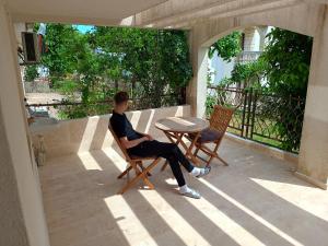 a man sitting in a chair on a patio at Jasmin 2 in Ulcinj