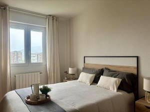 a bedroom with a large bed with two windows at Vistas al mar, a 1 min de la playa, terraza, wifi in Laredo