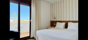 a bedroom with a bed and a large glass window at Hostal Playa in Punta Umbría