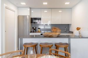 Una cocina con gabinetes blancos y taburetes de bar. en Casa Cala Serena, en Mijas