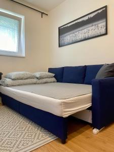 a bed in a room with a blue couch at Cozy Self check-in Apartment in vibrant Ruzinov area, Komárnická 42, Bratislava in Bratislava +9 photos