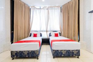 dwa łóżka w pokoju z oknem w obiekcie RedDoorz at Sparkling Hotel Surabaya w mieście Surabaja
