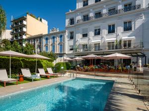 une piscine avec chaises et parasols à côté d'un bâtiment dans l'établissement Hôtel Le Canberra, à Cannes