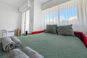 a bedroom with a green bed with a large window at Studio cosy clim - Piscine - Plage à pied - Cap d'Agde in Cap d'Agde