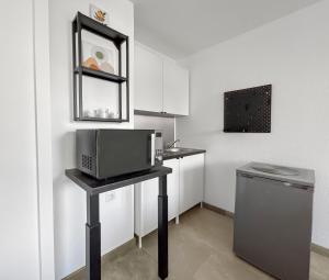 a small kitchen with a microwave on a table at Studio cosy clim - Piscine - Plage à pied - Cap d'Agde in Cap d'Agde +18 photos