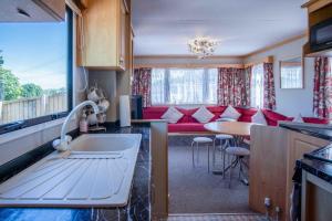 a kitchen with a couch and a table in a room at Hopkins Retreat - 3 Bedroom Caravan - Hot Tub in Swansea