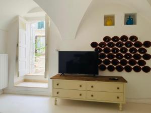 een woonkamer met een tv en een ladekast met een heleboel flessen wijn bij Casa L'Isule in Cisternino