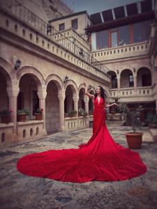 a woman in a red dress standing in front of a building at Nature Park Cave Hotel in Goreme
