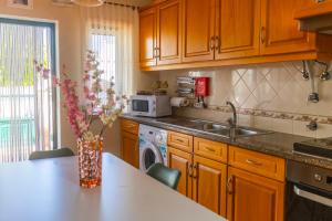 a kitchen with wooden cabinets and a vase of flowers on a counter at Moradia Valdemar in Nazaré
