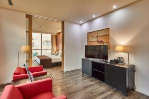 a living room with a television and red chairs at Silken Puerta Valencia in Valencia