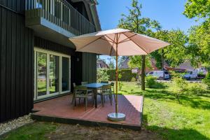 a patio with a table and chairs and an umbrella at Ostseedomizil "Ankerbuk", Ferienhaus Silberreiher in Born