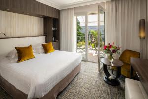 une chambre d'hôtel avec un lit et une table avec un vase de fleurs dans l'établissement Hôtel Le Canberra, à Cannes 37 autres photos