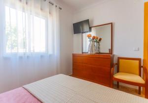 a bedroom with a bed and a dresser and a mirror at Moradia Valdemar in Nazaré
