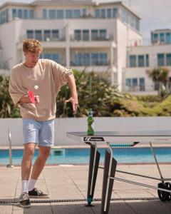 ein Mann steht mit einer Flasche neben einem Tisch in der Unterkunft St Moritz Hotel Houses in Polzeath