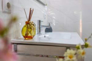 a bathroom sink with a vase with sticks in it at Moradia Valdemar in Nazaré +12 photos