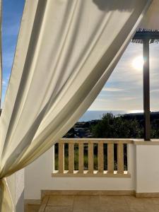 a view from a balcony with a white curtain at CASA MELODIA - immersa negli uliveti con vista sul mare Ionio in Marina San Gregorio