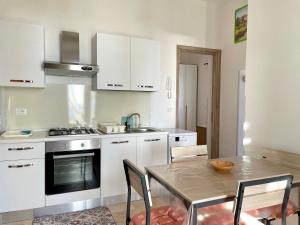 a kitchen with white cabinets and a table with chairs at CASA MELODIA - immersa negli uliveti con vista sul mare Ionio in Marina San Gregorio +58 photos
