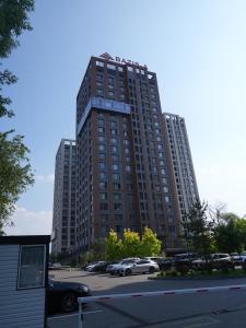 阿拉木图Primavera Hotel的一座高楼，停车场里停满了汽车