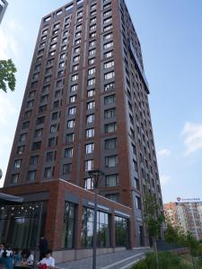 阿拉木图Primavera Hotel的一座高大的建筑,前面坐着人
