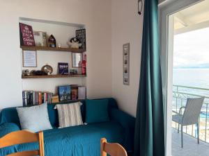 a living room with a blue couch and a balcony at Avra Benitses Beach Apartment in Benitses