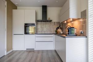 a kitchen with white appliances and wooden floors at Luxe villa aan golfbaan en bosrand in Appelscha in Appelscha +21 photos