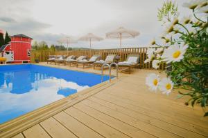 a swimming pool with chairs and umbrellas on a deck at Babka in Białka Tatrzańska