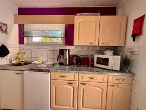 a kitchen with white cabinets and a sink and a microwave at Ferienhaus für drei Personen mit Terrasse in Friedrichroda