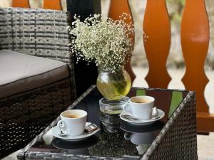a table with two cups of coffee and a vase of flowers at Holiday Home Manda in Tounj