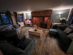 a living room with couches and a brick fireplace at Barn Cottage in Binton