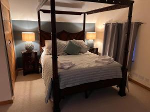a bedroom with a canopy bed and two lamps at Barn Cottage in Binton