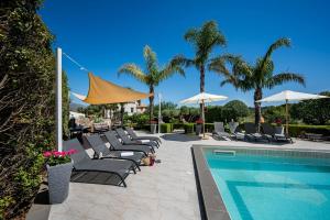 a group of chairs and umbrellas next to a swimming pool at Moresca Exclusive Villa - Pool & Spa in Castellammare del Golfo