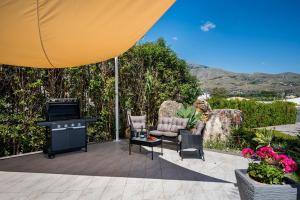 a patio with a television and chairs and a table at Moresca Exclusive Villa - Pool & Spa in Castellammare del Golfo