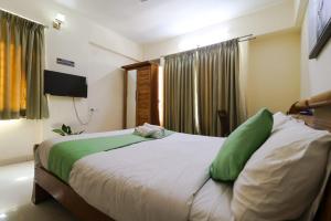 um quarto com uma cama grande e almofadas verdes em Hotel Grand View - Pimple Saudagar em Chinchwad