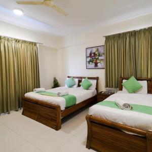 duas camas num quarto com cortinas verdes em Hotel Grand View - Pimple Saudagar em Chinchwad